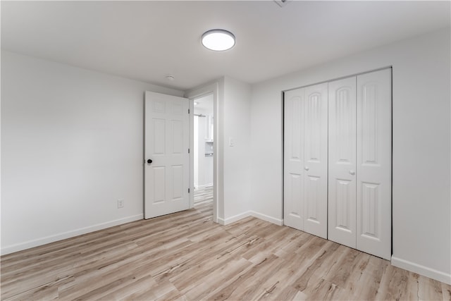 unfurnished bedroom featuring light hardwood / wood-style flooring and a closet