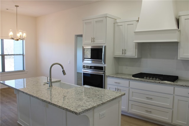 kitchen featuring a kitchen island with sink, sink, stainless steel appliances, and custom exhaust hood