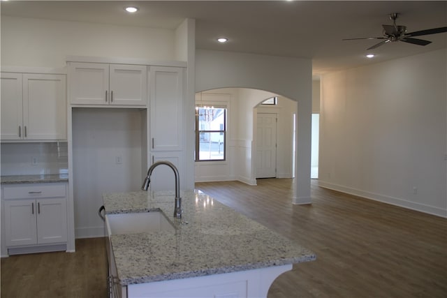 kitchen featuring a center island with sink, light stone countertops, white cabinetry, and sink