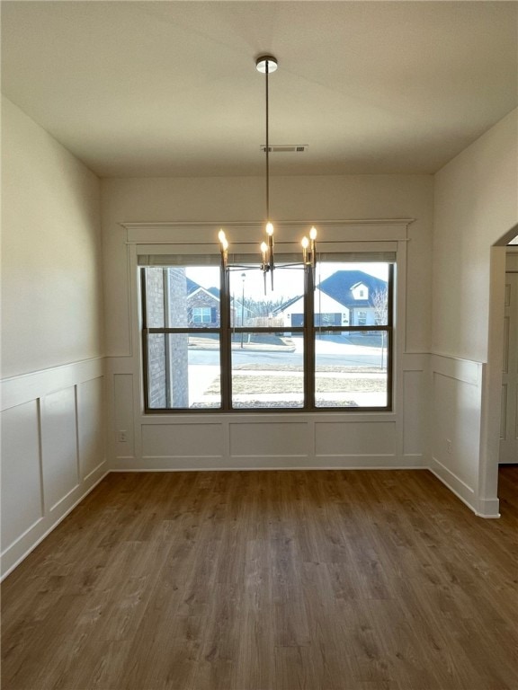 unfurnished dining area featuring dark hardwood / wood-style floors, a healthy amount of sunlight, and a notable chandelier