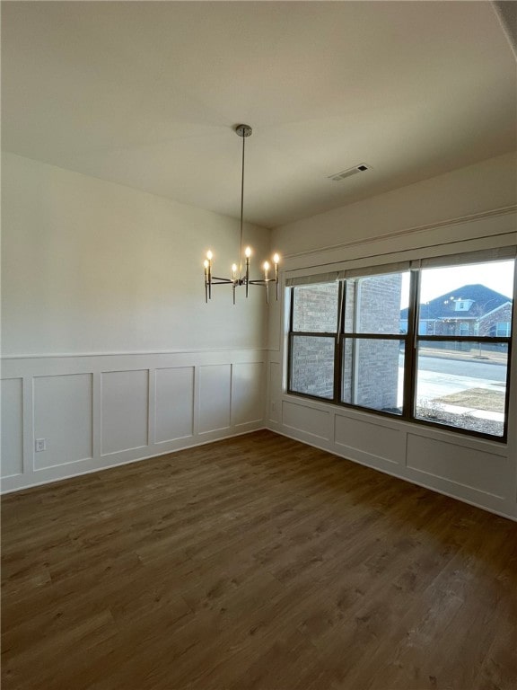 unfurnished dining area featuring dark hardwood / wood-style flooring and a chandelier