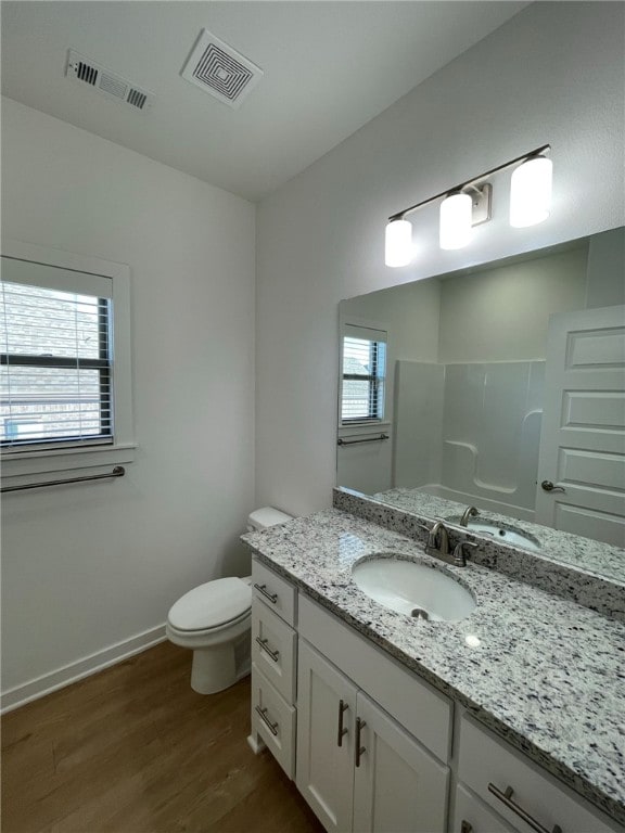 bathroom with a healthy amount of sunlight, a shower, wood-type flooring, and toilet