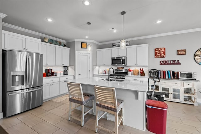 kitchen featuring appliances with stainless steel finishes, a kitchen breakfast bar, sink, a center island with sink, and decorative light fixtures