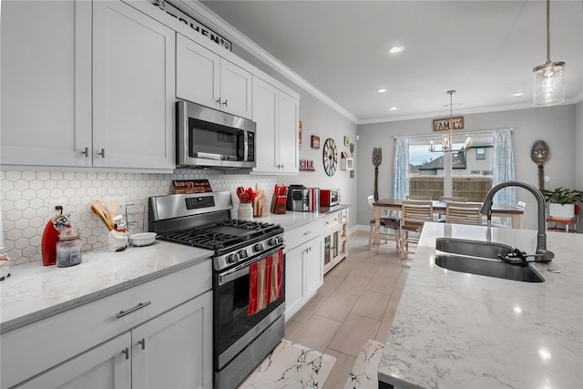 kitchen featuring light stone counters, sink, stainless steel appliances, and hanging light fixtures