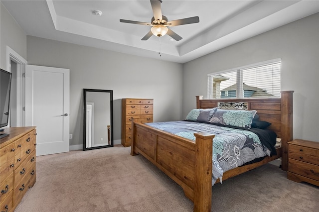 carpeted bedroom featuring a raised ceiling and ceiling fan