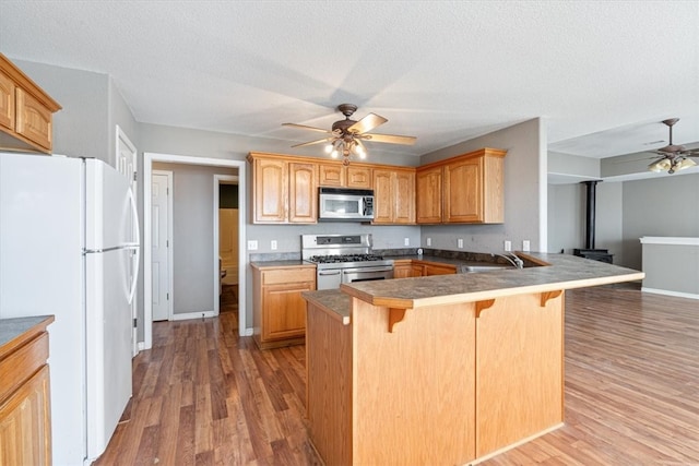 kitchen with kitchen peninsula, a breakfast bar, a textured ceiling, stainless steel appliances, and hardwood / wood-style floors