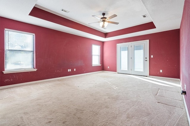 carpeted empty room featuring a tray ceiling and ceiling fan