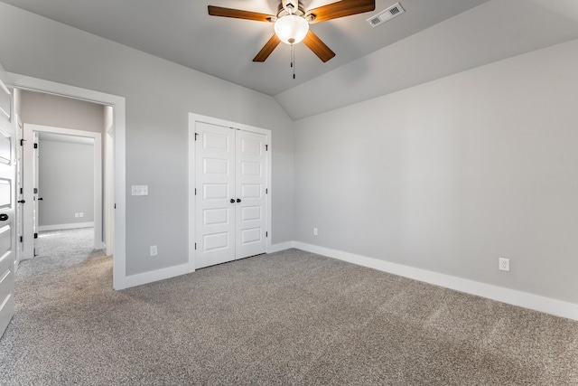 unfurnished bedroom featuring ceiling fan, a closet, carpet floors, and vaulted ceiling