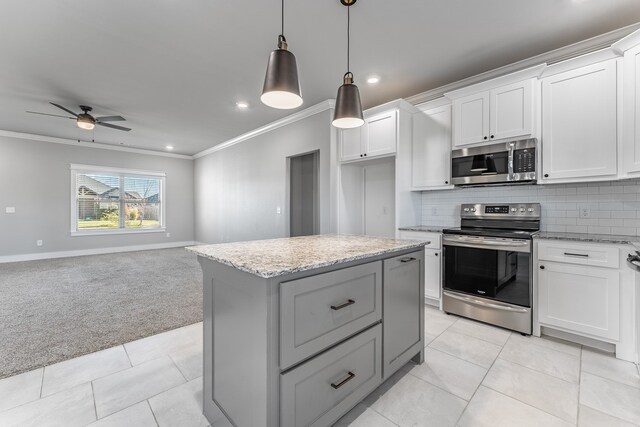 kitchen featuring stainless steel appliances, light colored carpet, white cabinets, a center island, and hanging light fixtures