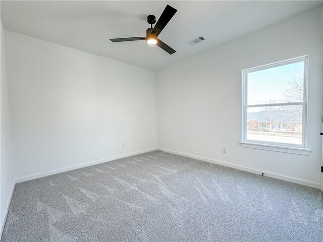 carpeted spare room with baseboards, visible vents, and ceiling fan