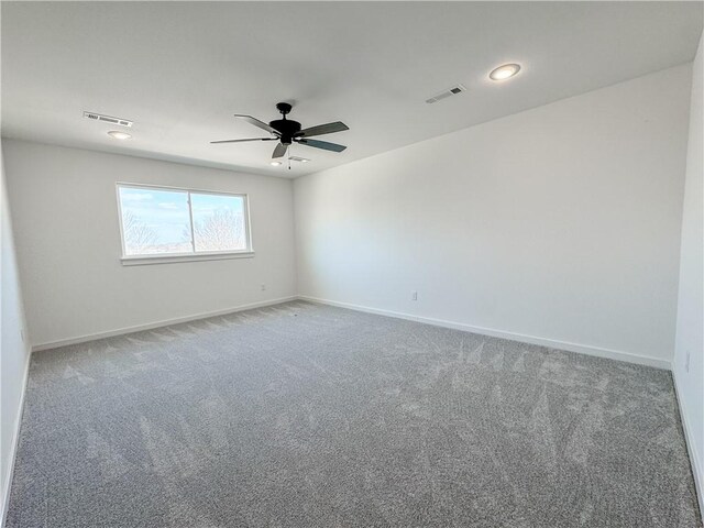 unfurnished room with ceiling fan, carpet flooring, visible vents, and baseboards