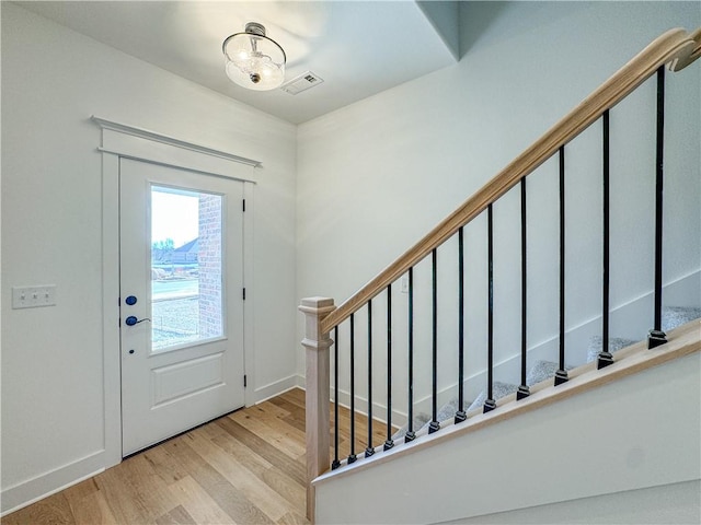 entryway featuring light wood-style floors, visible vents, baseboards, and stairs