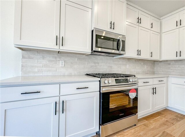 kitchen featuring light wood-style floors, tasteful backsplash, appliances with stainless steel finishes, and white cabinets