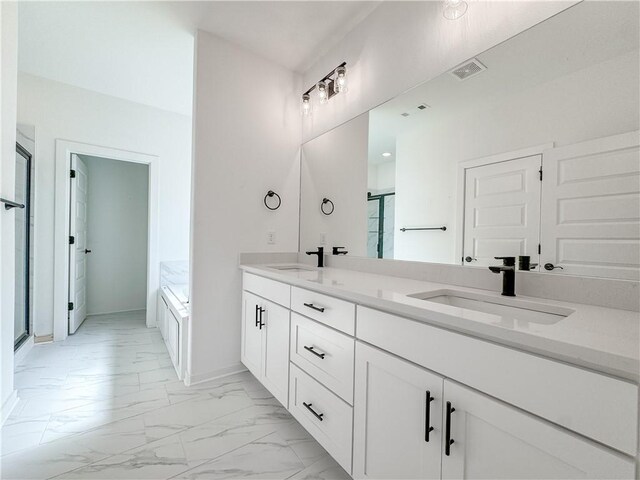 bathroom featuring marble finish floor, visible vents, a sink, and a bath