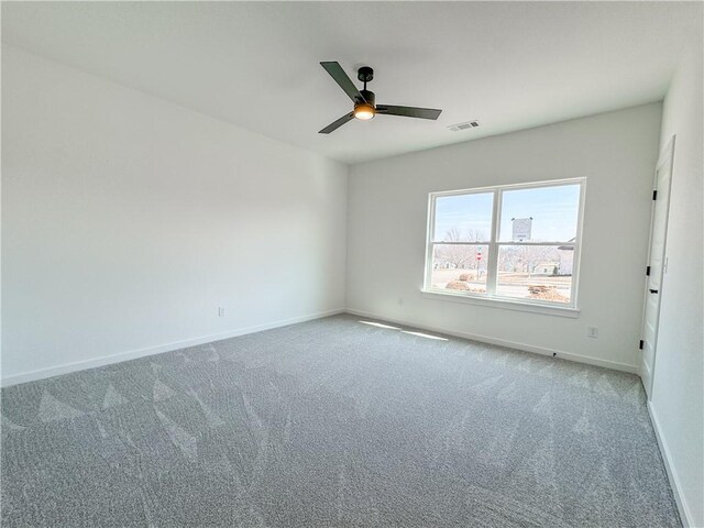 carpeted spare room featuring visible vents, a ceiling fan, and baseboards