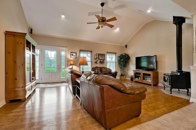 living room featuring ceiling fan, crown molding, high vaulted ceiling, light hardwood / wood-style floors, and a wood stove