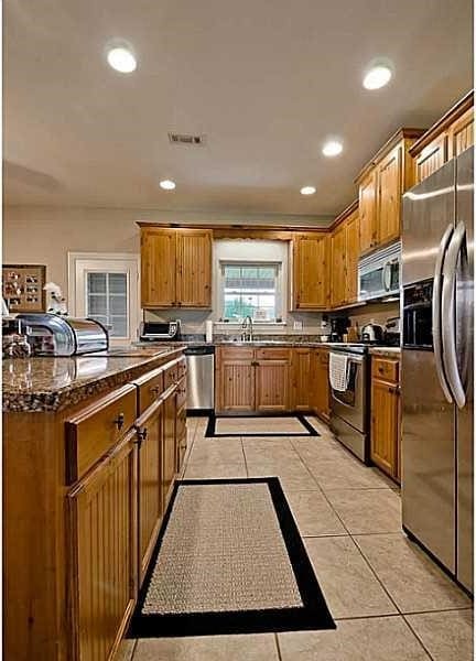 kitchen with dark stone countertops, light tile patterned floors, and stainless steel appliances