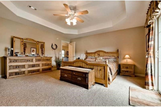 bedroom featuring a tray ceiling, ceiling fan, and light carpet