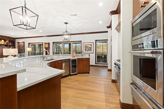 kitchen with pendant lighting, light wood-type flooring, stainless steel appliances, and sink