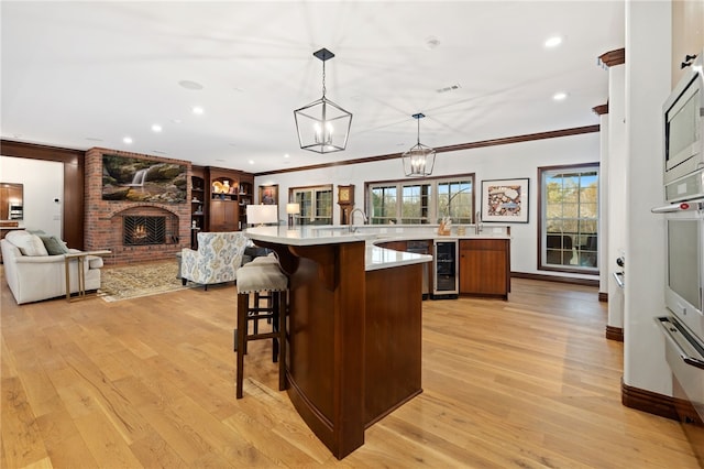 kitchen with a brick fireplace, a large island, pendant lighting, and light wood-type flooring