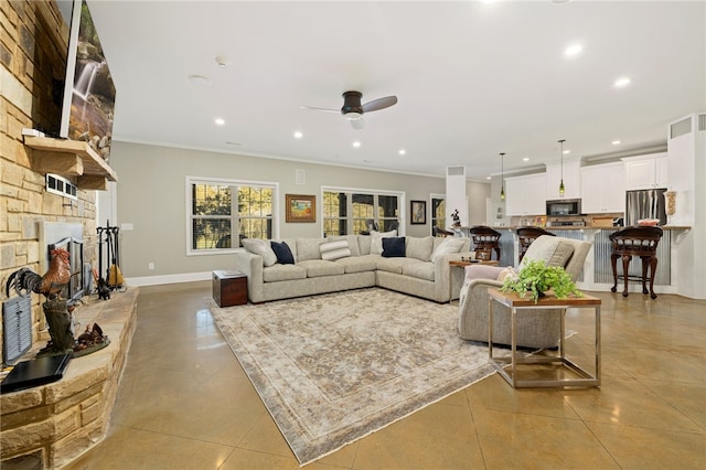 tiled living room featuring a stone fireplace, ceiling fan, and ornamental molding