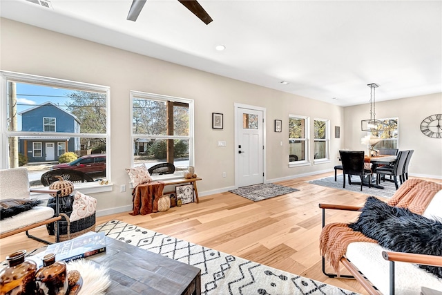 living room featuring ceiling fan with notable chandelier and light hardwood / wood-style floors