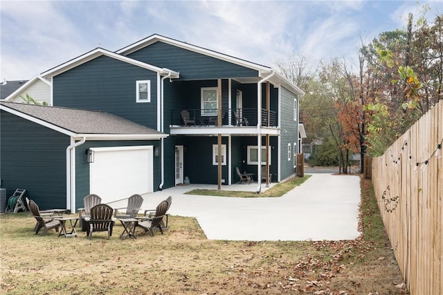 rear view of house with a garage, a patio, a balcony, and a fire pit