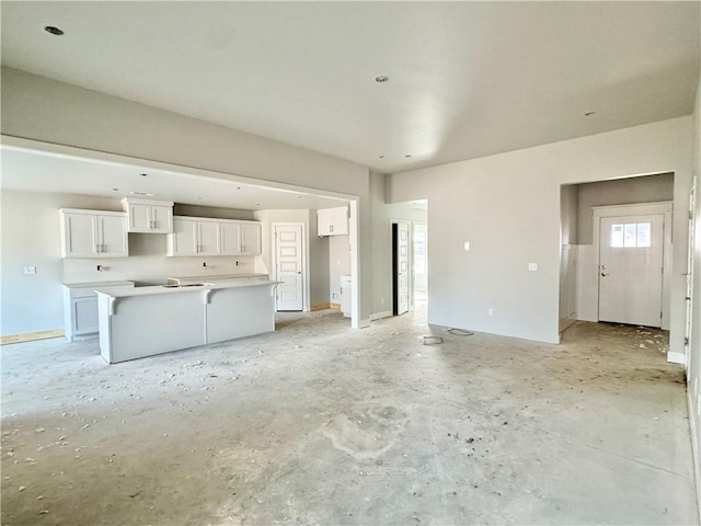 unfurnished living room with baseboards