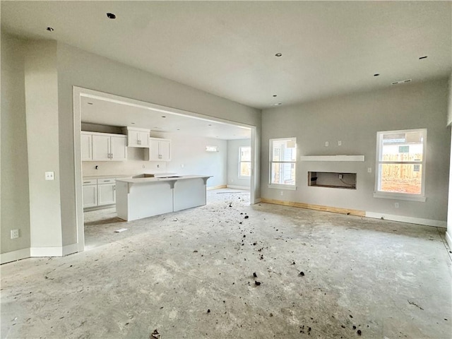 unfurnished living room with a fireplace, plenty of natural light, and baseboards