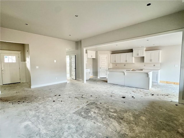 unfurnished living room with baseboards