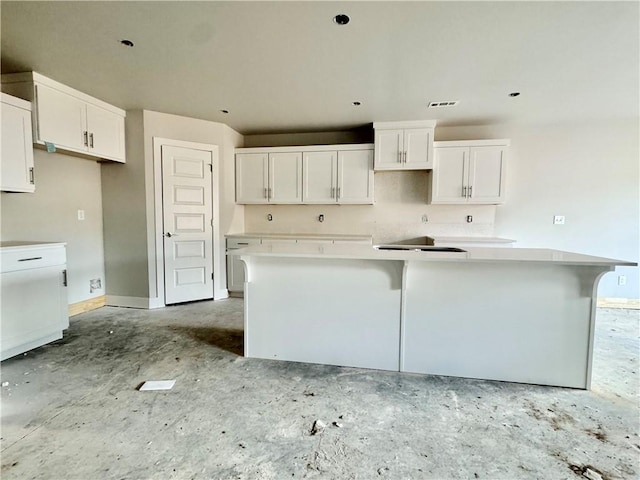 kitchen featuring visible vents, baseboards, white cabinetry, and a center island