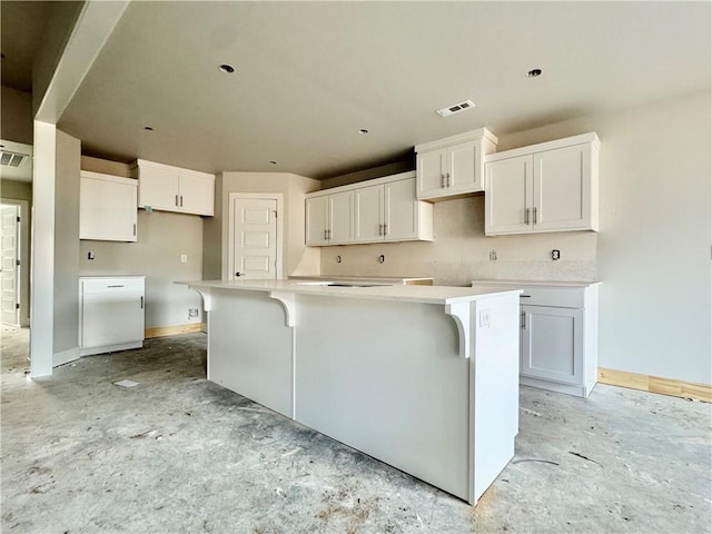 kitchen with baseboards, a kitchen island, visible vents, and white cabinets