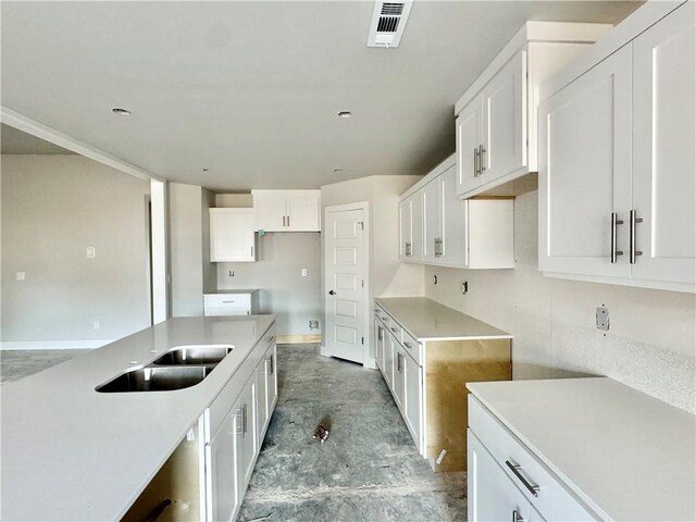 kitchen with unfinished concrete flooring, a sink, visible vents, and white cabinetry