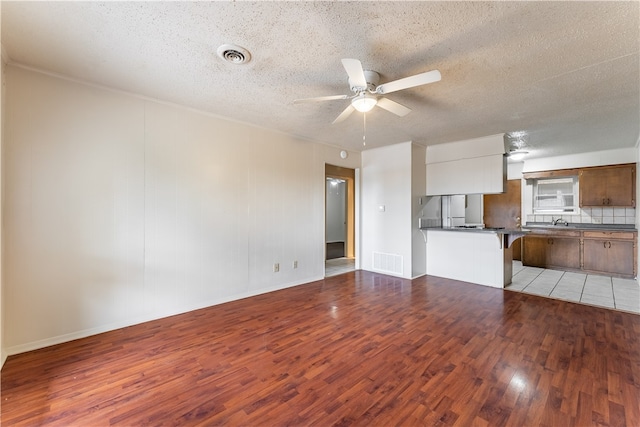 unfurnished living room with a textured ceiling, light wood-type flooring, and ceiling fan