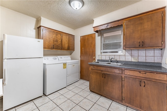 clothes washing area with cabinets, a textured ceiling, sink, light tile patterned floors, and washing machine and clothes dryer