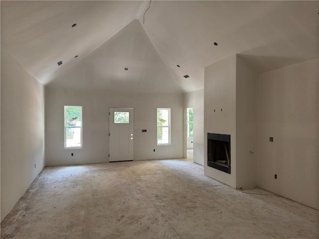 unfurnished living room with high vaulted ceiling and a healthy amount of sunlight