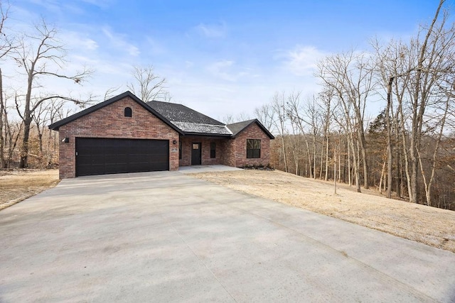 view of front of house featuring a garage, driveway, brick siding, and roof with shingles