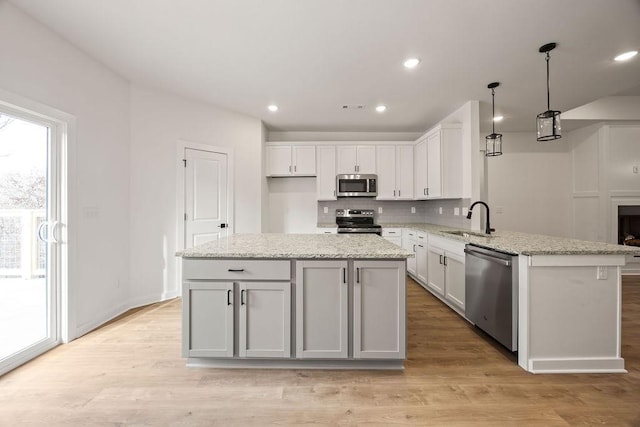 kitchen featuring light wood finished floors, decorative backsplash, stainless steel appliances, and a sink