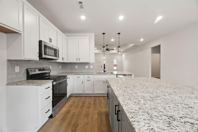 kitchen with recessed lighting, stainless steel appliances, a sink, white cabinetry, and light wood-style floors