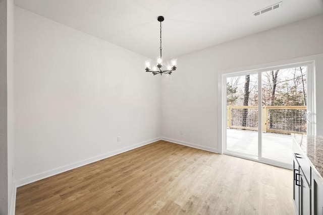 unfurnished room with light wood-type flooring, visible vents, baseboards, and an inviting chandelier