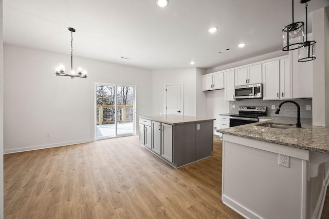 kitchen featuring light stone counters, stainless steel appliances, a sink, light wood-style floors, and backsplash