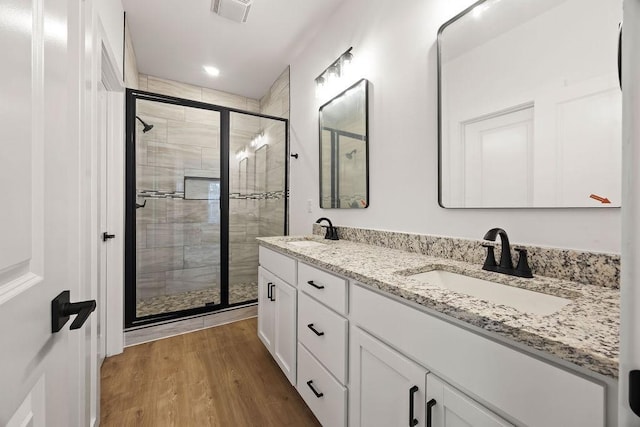 full bath featuring wood finished floors, a stall shower, a sink, and visible vents