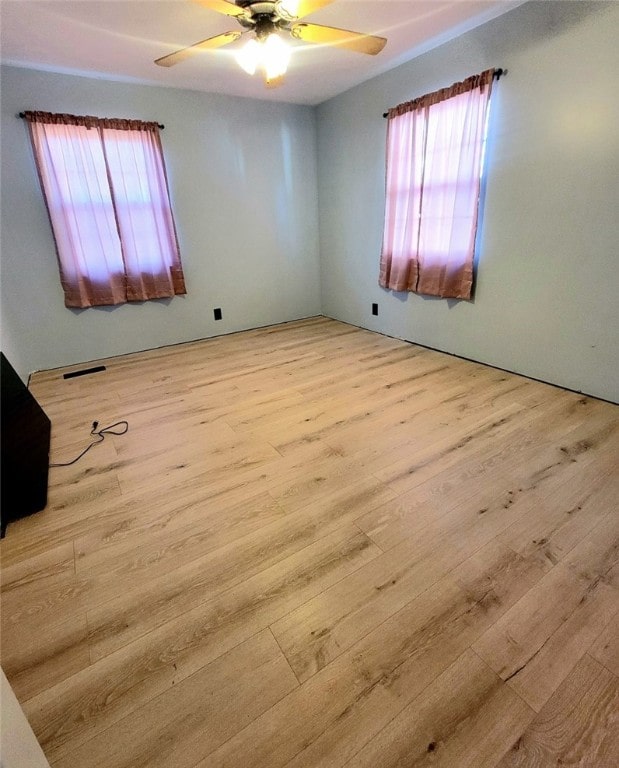 unfurnished room featuring ceiling fan, light hardwood / wood-style flooring, and a healthy amount of sunlight