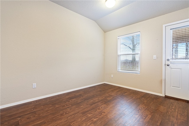 interior space with a textured ceiling, dark hardwood / wood-style flooring, and lofted ceiling