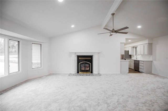 unfurnished living room featuring lofted ceiling with beams, dark carpet, ceiling fan, and sink