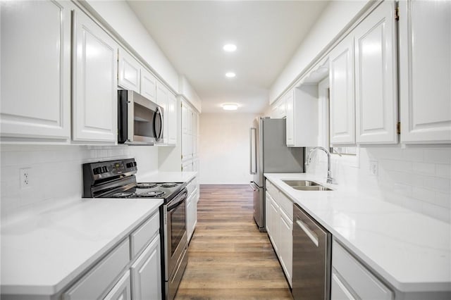 kitchen with white cabinets, sink, light hardwood / wood-style flooring, light stone counters, and stainless steel appliances