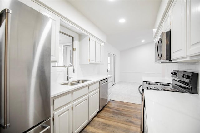 kitchen featuring backsplash, stainless steel appliances, sink, hardwood / wood-style flooring, and white cabinets