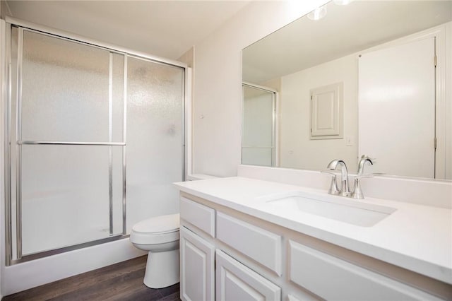 bathroom with hardwood / wood-style flooring, vanity, toilet, and a shower with door