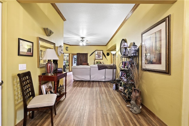 living room with a textured ceiling, ceiling fan, wood-type flooring, and crown molding