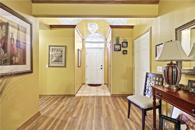 foyer entrance with beamed ceiling, a chandelier, and light hardwood / wood-style flooring